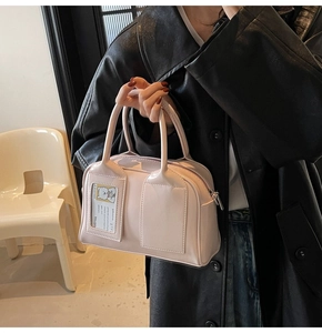 Detail showing the light beige bowling bag with a cute bear card slot and silver zipper
