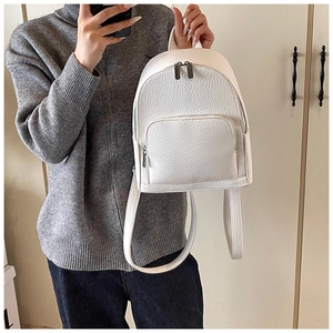 Detailed macro view of the white lychee textured leather and metal hardware on the backpack