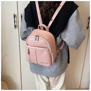 Rear view of a pink pebbled leather mini backpack worn by a model in a stylish setting
