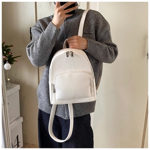 Mirror selfie showing the white pebble leather backpack on a model in a home setting