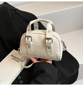 Détail d'un sac à main vintage blanc crème avec finition brillante et boucles décoratives