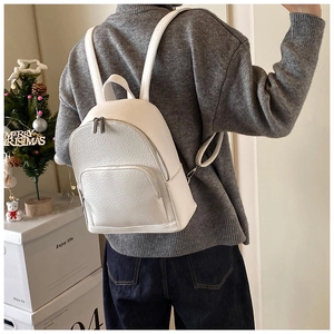 Close-up of white pebble grain faux leather backpack with silver zippers on model
