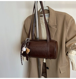 Detail of vintage brown barrel bag with relief lettering and baseball glove charm