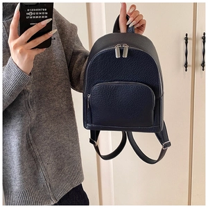 Detail of dark blue pebbled leather backpack with silver metal zippers and front pocket