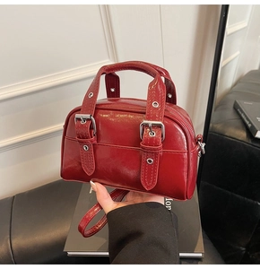 Détail d'un mini sac Boston en cuir verni rouge foncé brillant avec clous argentés