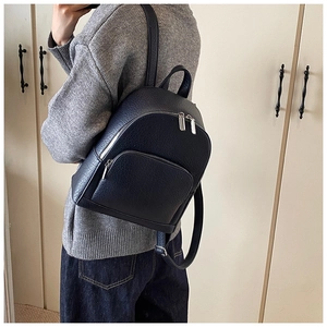 Detailed side view of black litchi pattern leather backpack showing silver hardware