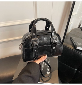 Détail du sac Boston noir brillant avec rivets argentés et bandoulière amovible