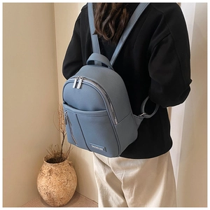 Detail of blue litchi pattern leather backpack with metal logo and zipper texture