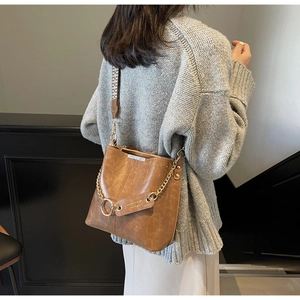Détail du sac seau vintage marron avec chaîne dorée et large bandoulière tissée