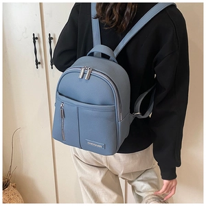 Detail of light blue pebble leather mini backpack showing double zippers and metal logo
