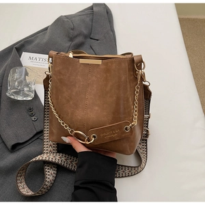 Détail du sac seau marron rétro avec chaîne dorée et bandoulière motif pied-de-poule