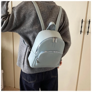 Detail of light blue pebble grain leather mini backpack with silver zipper on a model