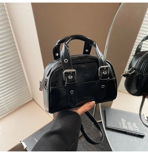 Détail du sac à main noir brillant avec boucles argentées et bandoulière réglable