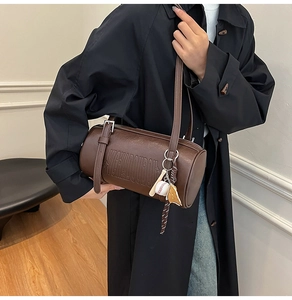 Detail view of coffee brown retro cylinder bag with embossed letters and baseball charm