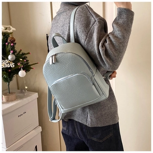 Close-up of light blue pebbled leather backpack with zipper detail and adjustable straps