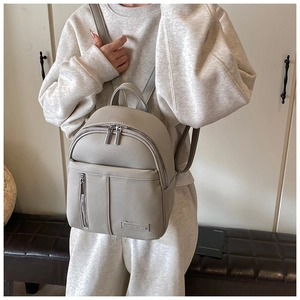 Detail of the light grey pebble grain leather backpack showing texture and silver hardware
