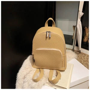 Detail view of beige lychee texture faux leather backpack with silver metal zippers