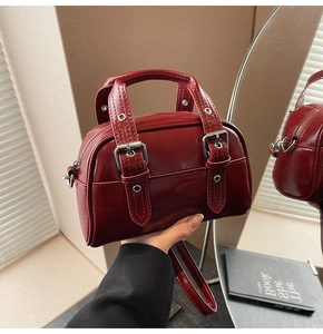 Détail du sac en cuir verni bordeaux avec boucles en métal argenté et poignées