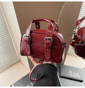 Gros plan d'un sac à main rétro bordeaux avec boucles argentées et finition brillante