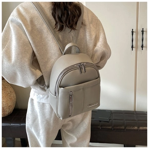 Close-up of a grey mini leather backpack featuring lychee texture and silver zipper detail