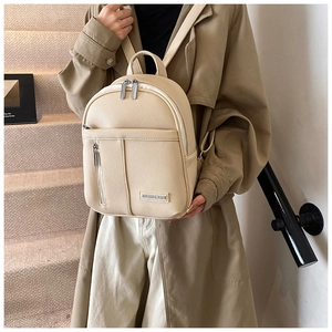 Detail shot of beige faux leather backpack with fine lychee texture and silver zippers