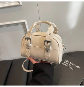 Détail d'un mini sac à main blanc cassé avec œillets métalliques argentés et doubles anses