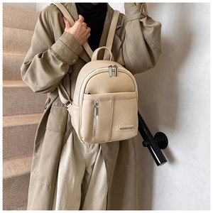 Close-up of beige lychee texture leather backpack with silver zippers and metal logo