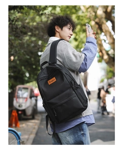 Detail of durable black nylon backpack with orange Tengrun label in city street setting