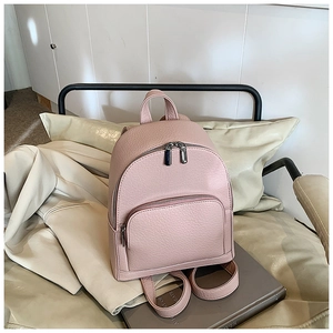 Detail of light pink mini backpack with litchi texture and silver hardware on a chair
