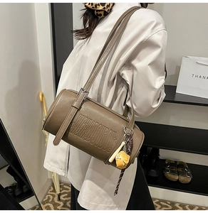 Detail of vintage brown cylinder shoulder bag with embossed letters and wood bag charm