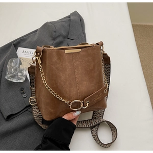Détail d'un sac seau marron avec chaîne dorée et bandoulière en jacquard à motifs