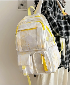 Detail of white canvas backpack featuring yellow accents and multiple storage compartments