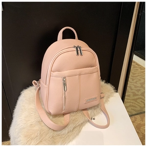 Close-up of pink lychee grain leather backpack with dual zippers and metal buckle