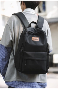 Outdoor shot showing the back of a black minimalist backpack with cushioned straps