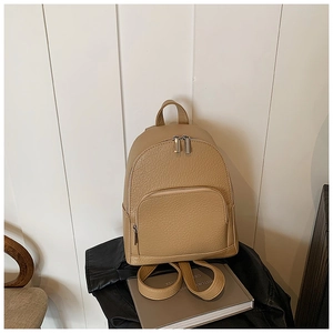 Detailed shot of khaki pebble leather backpack with silver zippers on stacked books