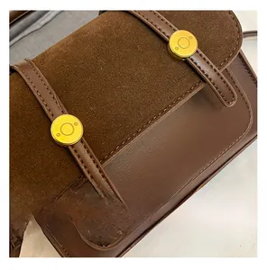 Detail view of dark brown vintage crossbody bag showing suede flap and gold metal buckles