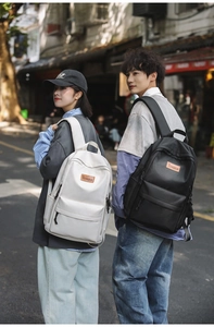 Outdoor street scene featuring couple wearing black and cream minimalist travel backpacks