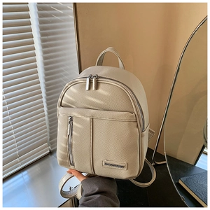 Detailed macro shot of the cream white lychee texture leather and silver zipper on the mini backpack