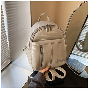 Detail of off-white backpack showing lychee texture leather and metal logo plaque