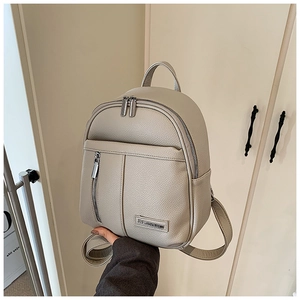 Close-up of lightweight beige backpack with litchi texture leather and metal logo plaque