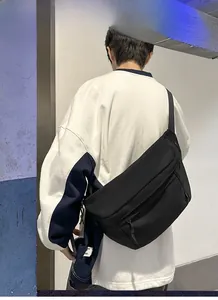 Rear view of a black high-capacity messenger bag with adjustable wide strap on model