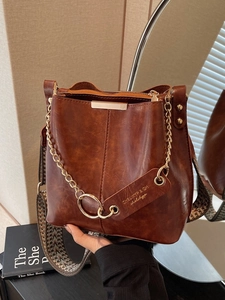 Sac seau vintage marron en cuir avec bandoulière tissée et chaîne métallique