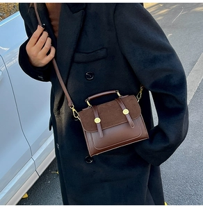 Detail view of retro brown crossbody bag with matte flap and gold decorative buckles
