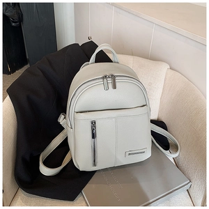 Detail of light grey lychee texture leather backpack with metallic logo and zippers