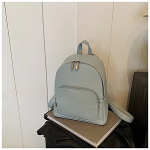 Detailed macro view of the light blue-green pebbled leather texture and zipper of the backpack
