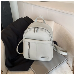 Close-up of light grey litchi texture leather backpack with silver metal zippers