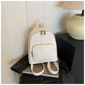 Detail of white lychee texture PU leather backpack with silver zippers on books