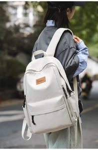 Detail view of the side profile on a cream canvas backpack with a leather logo patch