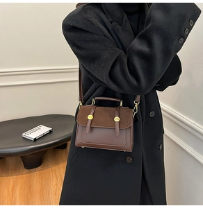 Detail of vintage crossbody bag in dark brown leather being worn by a model in a black coat
