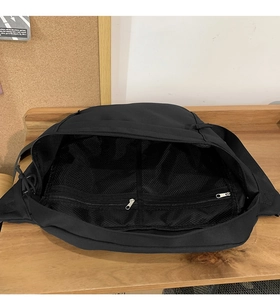 Interior view of black crossbody bag showing mesh compartments and metal zipper pockets